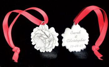 Two pewter flower ornaments with red ribbons.