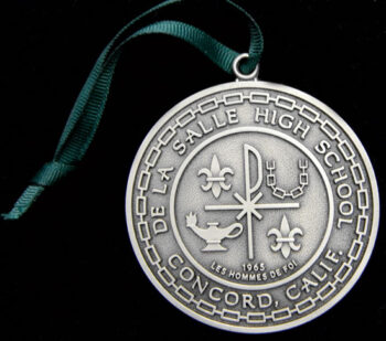 A silver De La Salle High School medallion.