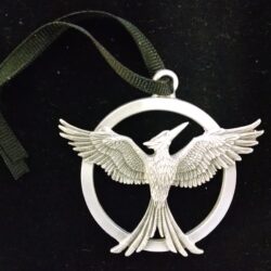 A silver Mockingjay pendant on a black background.