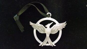 A silver Mockingjay pendant on a black background.