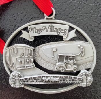 A silver ornament with The Villages logo.